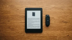 Kindle sobre mesa de madeira com passador de página ao lado — os 3 melhores passadores de página para Kindle disponíveis na Amazon Brasil em 2026.