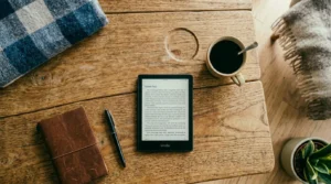 Kindle sobre mesa de madeira ao lado de xícara de café e passaporte representando leitura offline sem precisar de internet