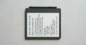 Kindle Scribe com caneta sobre superfície clara mostrando anotações manuscritas na tela e-ink de 11 polegadas